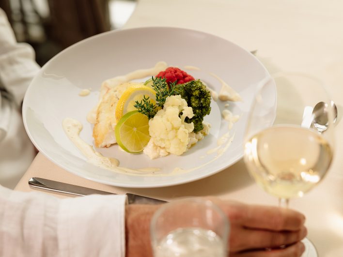 Abendessen im Hotelrestaurant: Fischfilet mit heller Sauce, Blumenkohl, Brokkoli und Zitrone, dazu ein Glas Weißwein.