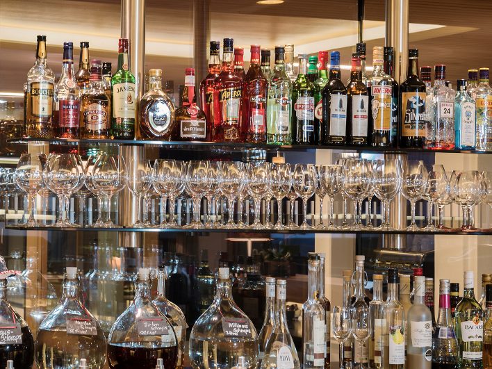 Gut bestücktes Barregal der Wälderbar mit Whisky, Gin und Aperitifs, darunter bauchige Glasballons mit Marillen-, Zirben- und Williamsschnaps.