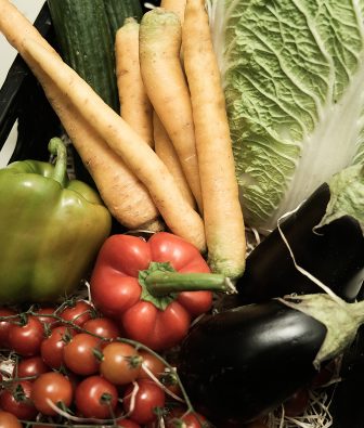 Kiste mit frischem Gemüse, darunter Karotten, Chinakohl, Paprika, Auberginen, Gurke und Rispentomaten