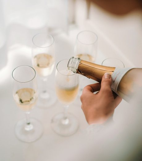 Sekt wird zum Anstoßen in mehrere Sektgläser eingeschenkt.